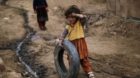 A young Afghan refugee girl plays with a tire in an alley of a poor neighborhood of Rawalpindi, Pakistan, Friday, Feb. 19, 20
