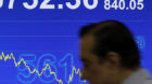 A man walks past a screen displaying the Hong Kong stock index's movement at a stockbrokerage firm in Hong Kong Monday, Oct.