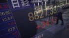 People walk in front of the electronic stock board of a securities firm in Tokyo, Japan, Tuesday, Jan. 31, 2012. Asian stocks