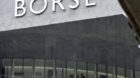 A man walks behind a window front of the Swiss Stock Exchange SWX, as a chart shows a falling index, in Zurich Switzerland on