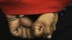 A handcuffed detained suspect is is shown to the press during a news conference at the state police after a bomb threat in Ti