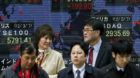 Pedestrians wait to cross an intersection in front of an electronic stock board of a securities firm in Tokyo, Thursday, Marc