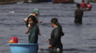 A Thai family wades through a flooded street on the outskirts of Bangkok, Thailand, Thursday, Nov. 24, 2011. Since July, more
