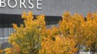 Autumn-colored trees stand in front of the Swiss Stock Exchange SWX, as a chart shows a falling index, in Zurich Switzerland