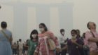 Tourists visit a sightseeing spot as the Marina Bay Sands Hotel in the background is shrouded with haze in Singapore on Satur
