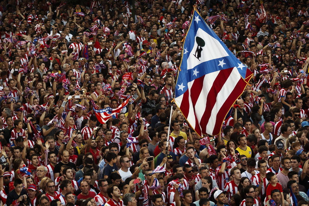 Atletico de Madrid supporters wave a flag with their team emblem as they celebrate the Spanish first division title ''La Liga'' with his team players at the Neptuno fountain in Madrid, Sunday May 18, 2014. A 1-1 draw against Barcelona on the last match ga