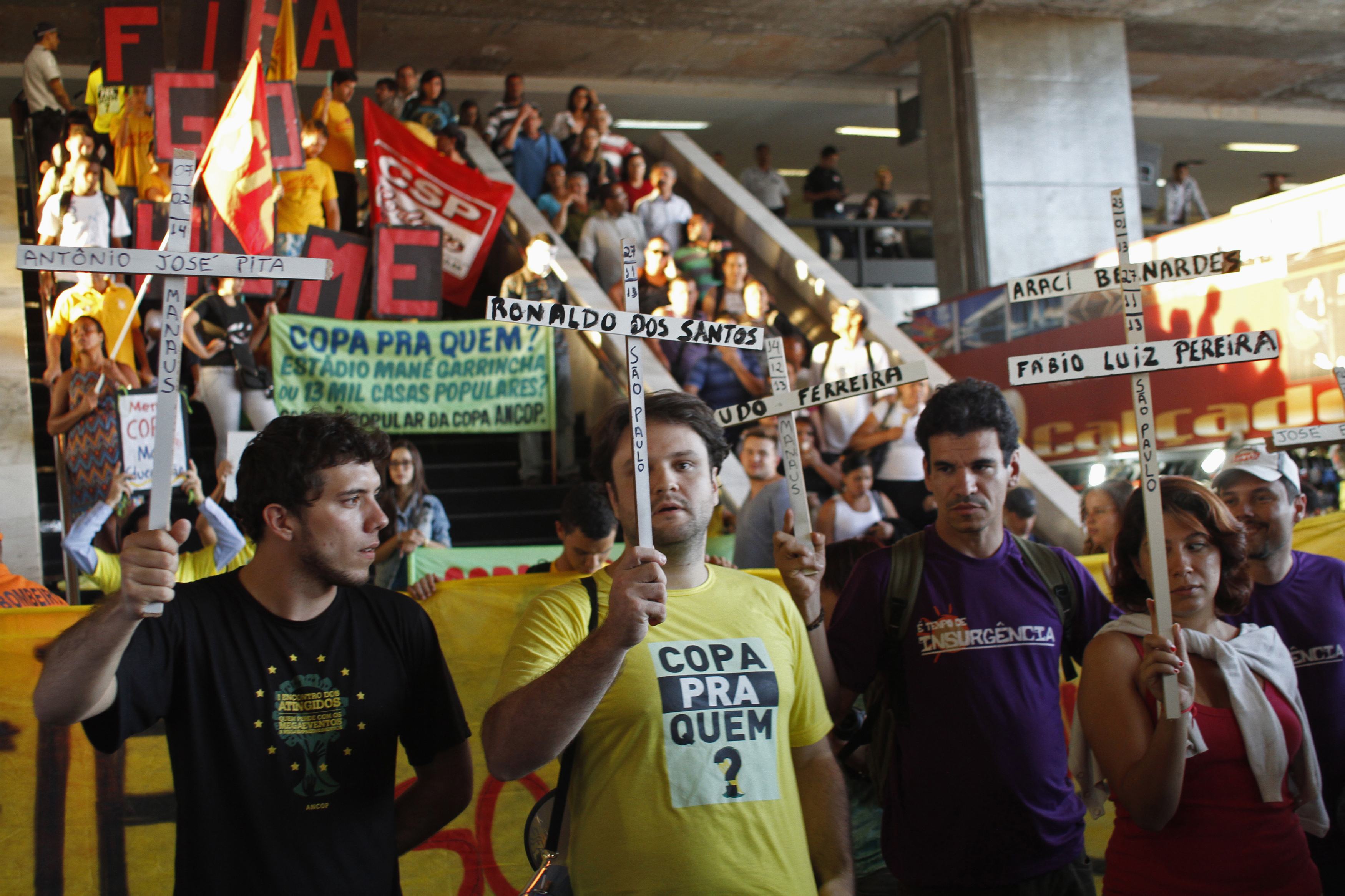 Demonstrators protest against the 2014 World Cup holding crosses etched with names of construction workers who died building the stadiums, in front of a major bus terminal in Brasilia May 15, 2014. Brazilians opposed to the World Cup and the public funds 