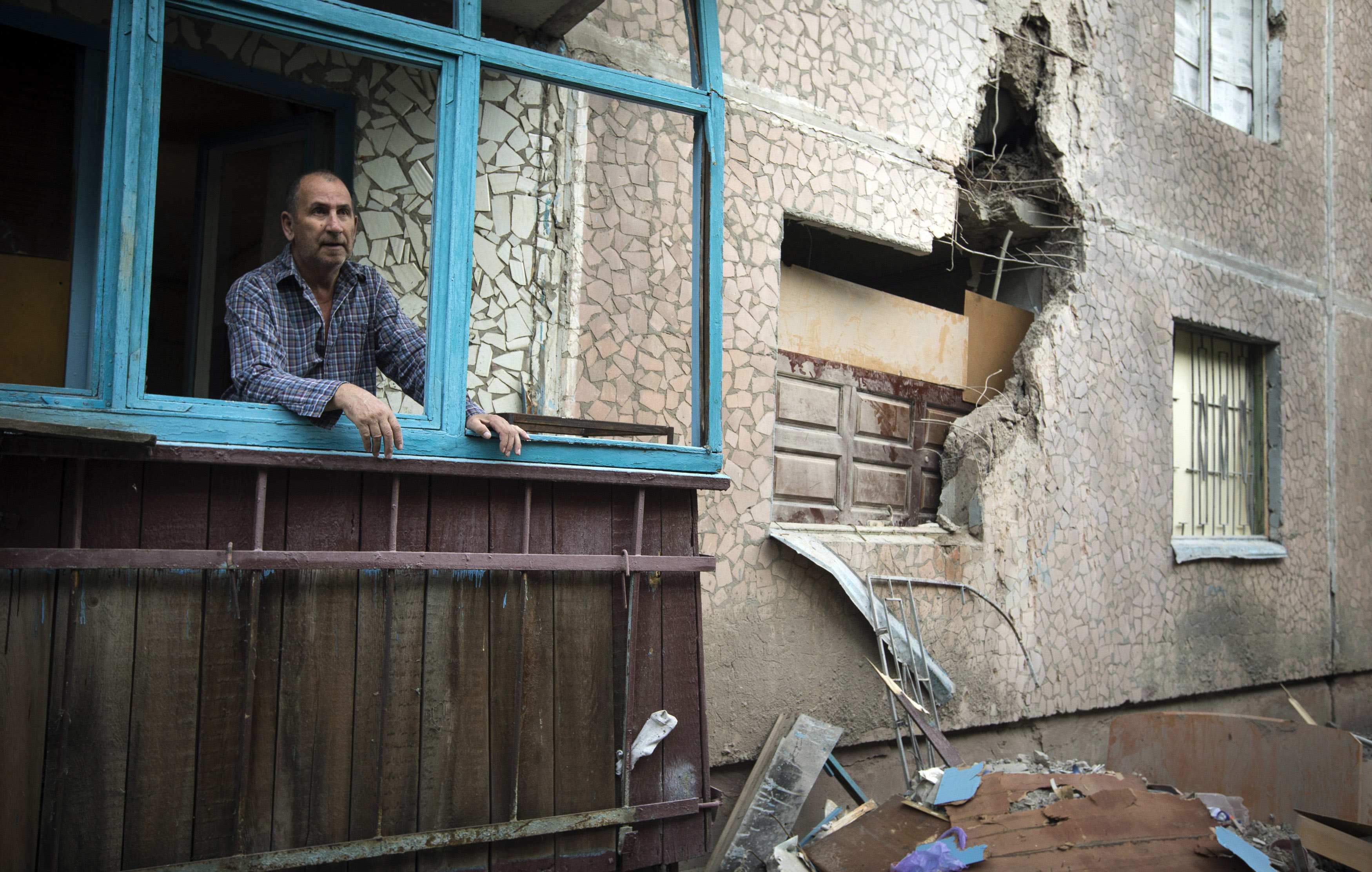 Valery, 63, looks out of a window of his apartment, which was damaged by shelling, in Slaviansk in eastern Ukraine June 30, 2014. About half the 130,000 residents of Slaviansk are thought to have fled since fighters who want eastern Ukraine incorporated i