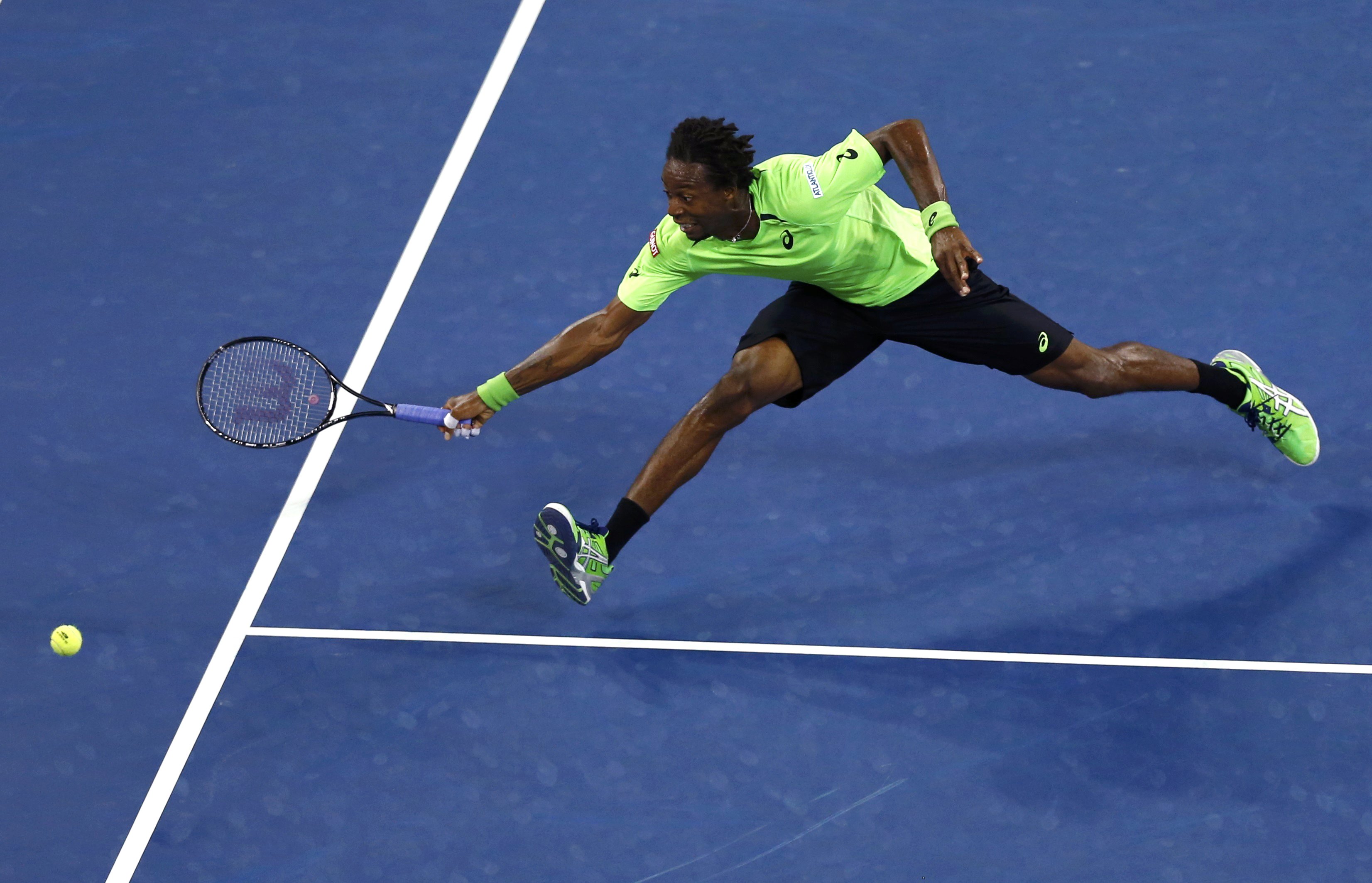 Gael Monfils of France stretches to try and make a return in the fourth set to Roger Federer of Switzerland during their quarter-final men's singles match at the 2014 U.S. Open tennis tournament in New York, September 4, 2014. REUTERS/Adam Hunger (UNITED 