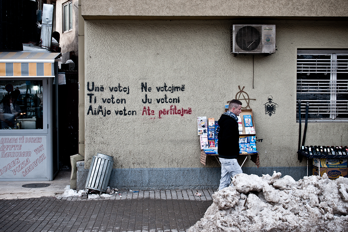 Sprayerei, Andeutung an die herrschende Korruption: «ich wähle , du wählst, er/sie wählt, wir wählen, sie wählen, SIE GEWINNEN». Kosovo ist noch immer von wenigen Staaten anerkannt.