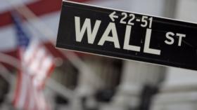 FILE - In this May 11, 2007, file photo, a Wall Street sign is mounted near the flag-draped facade of the New York Stock Exch