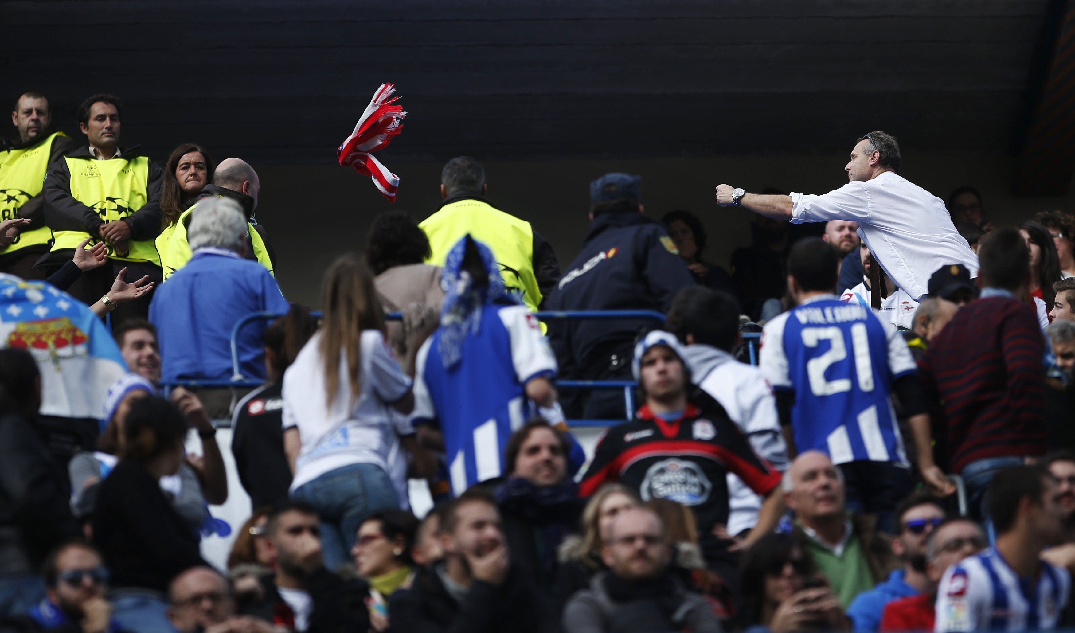 An Atletico Madrid fan (R) throws his team's scarf to Deportivo Coruna supporters during their Spanish first division soccer match at Vicente Calderon stadium in Madrid, November 30, 2014. A Deportivo La Coruna supporter was critically injured when dozens of rival fans clashed near the stadium before the club's La Liga match at Atletico Madrid on Sunday. REUTERS/Susana Vera (SPAIN - Tags: SPORT SOCCER)