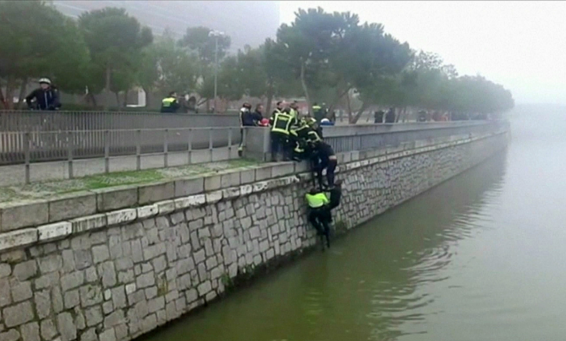 Helfer retten einen unbekannten Mann aus dem Fluss Manzanares in Madrid, wo in der Nähe des Stadions von Atletico gewalttätige Fangruppen sich eine Schlacht lieferten.
