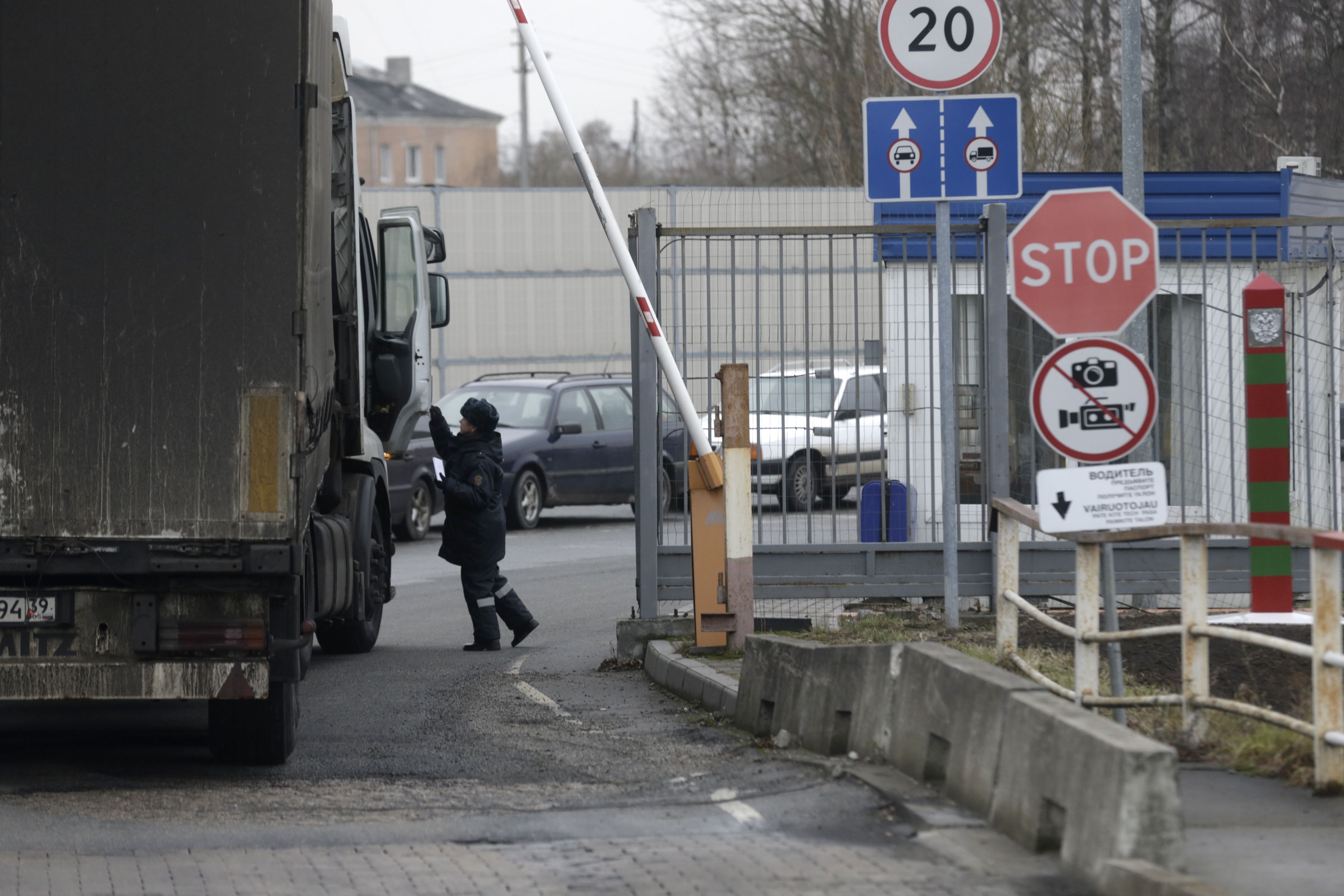 A Russian border guard inspects a truck as it enters Russia at a border crossing with Lithuania in Kybartai December 16, 2014. Tensions with Moscow have simmered ever since Lithuania became the first republic to declare independence from the Soviet Union in 1990, although only 6 percent of the population are Russian speakers, far fewer than in its Baltic neighbours. On Jan. 1, it will be the last of the Baltic states to join the currency bloc, hoping like Estonia and Latvia for more investment and lower borrowing costs to spur one of Europe�s poorest but fastest-growing economies. All three have felt the blowback from East-West tension over Russia's encroachment into Ukraine this year in the form of Russian sanctions and military grandstanding on their borders. Picture taken December 16, 2014. REUTERS/Ints Kalnins (LITHUANIA - Tags: POLITICS TRANSPORT BUSINESS)