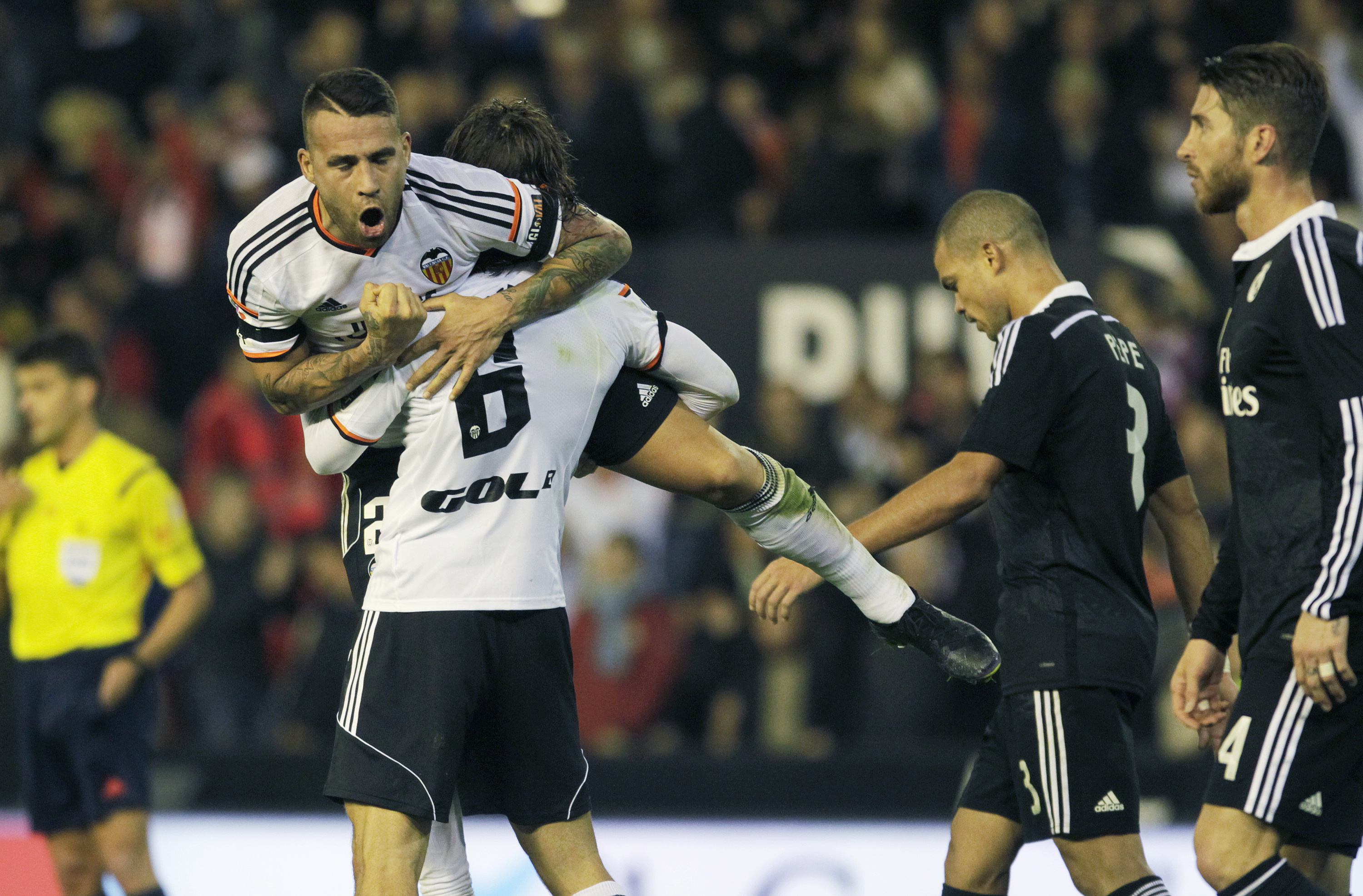 Valencia's Nicolas Otamendi (top) and Lucas Orban celebrate their victory over Real Madrid after their Spanish first division soccer match at the Mestalla stadium in Valencia, January 4, 2015. REUTERS/Stringer (SPAIN - Tags: SPORT SOCCER)