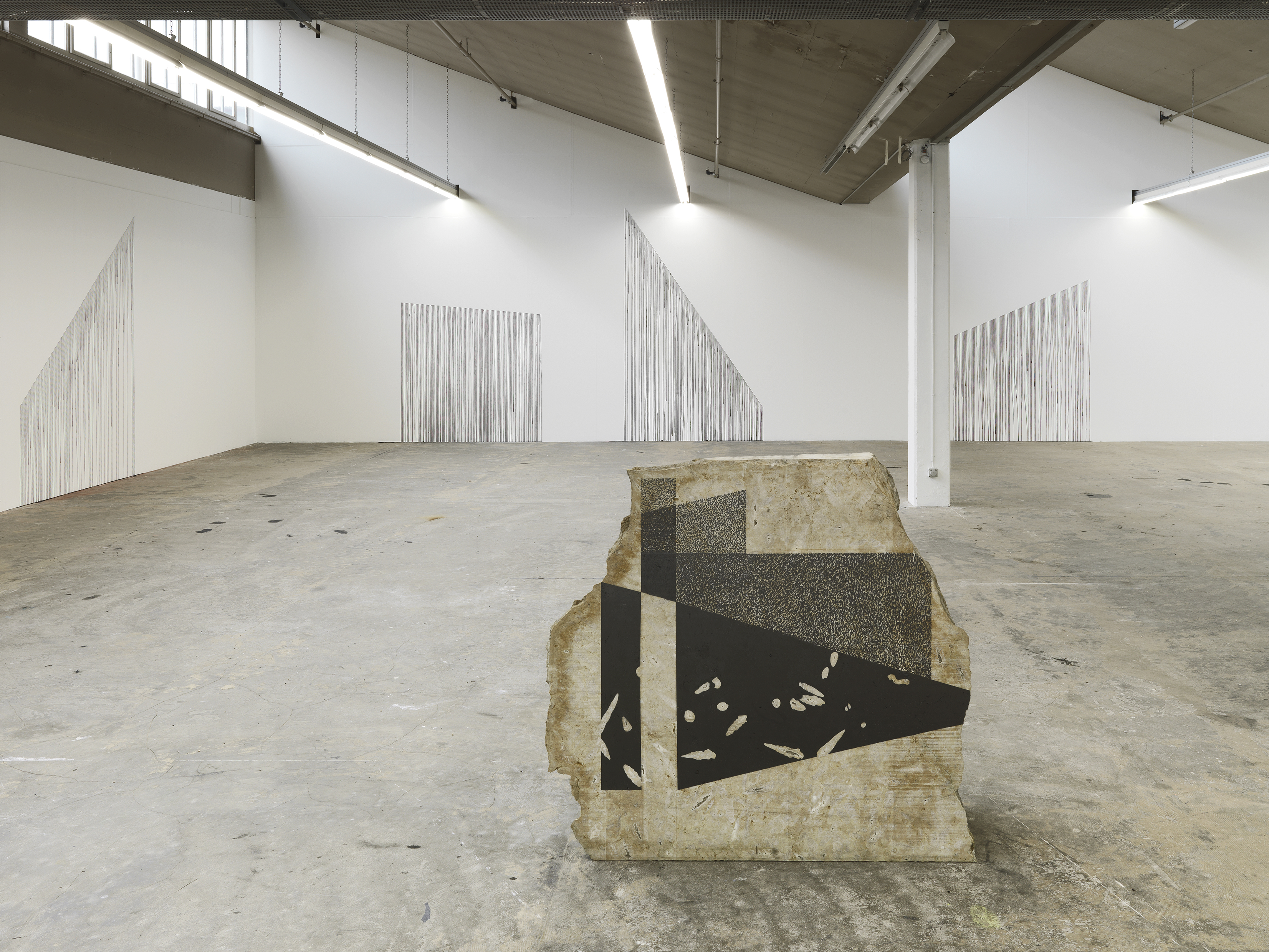 Jan Hostettlers Umgang mit Material: Mit Graphit bearbeitete Steinblöcke und Tuschespuren an der Wand.