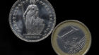 A Euro coin, right, and a Swiss Franc coin have been placed on a table to be photographed in Gelsenkirchen, Germany, Thursda