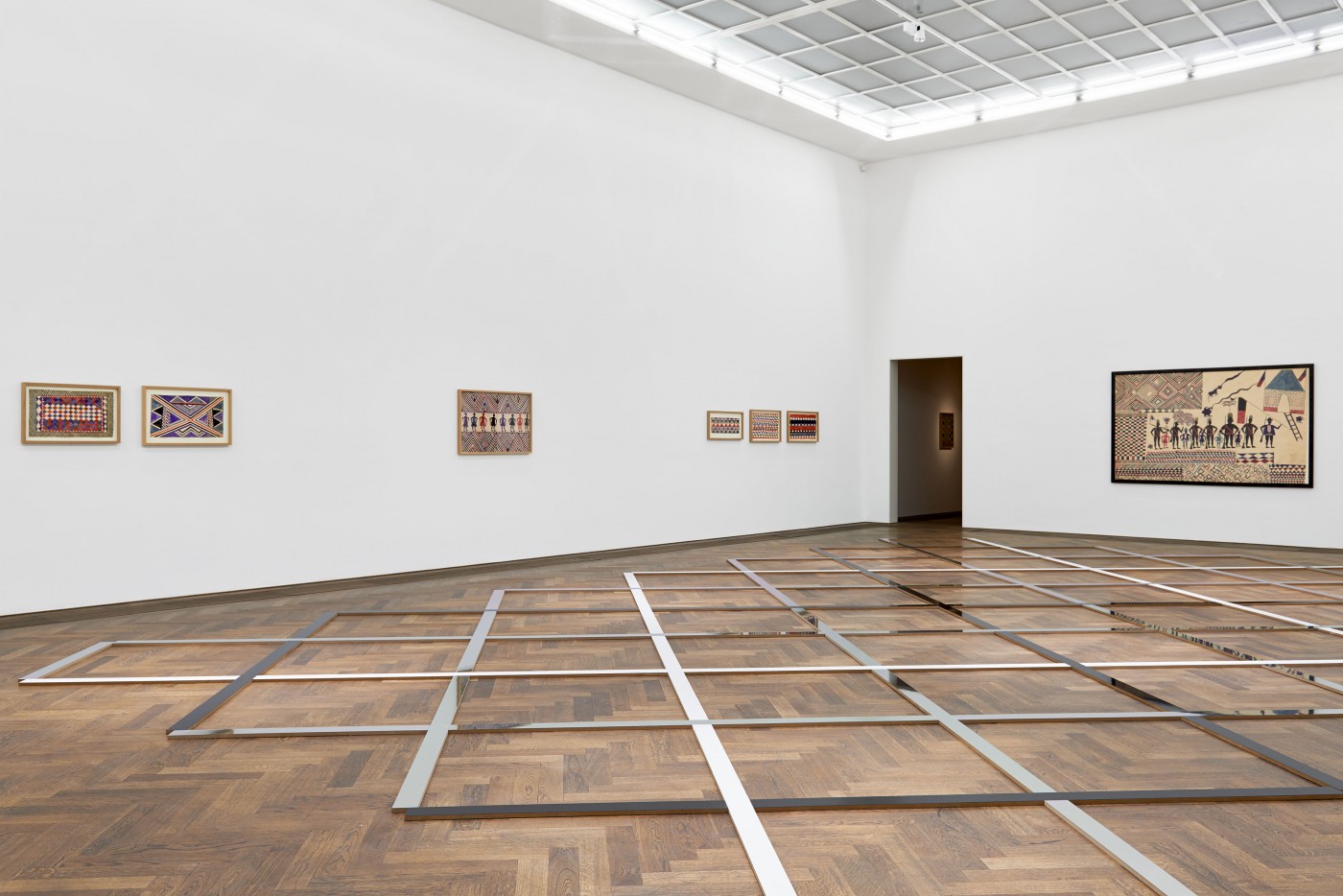 Die Installation am Boden nimmt die Boden- und Deckenstruktur wie auch die Muster in den Bildern von Thela Tendu auf.