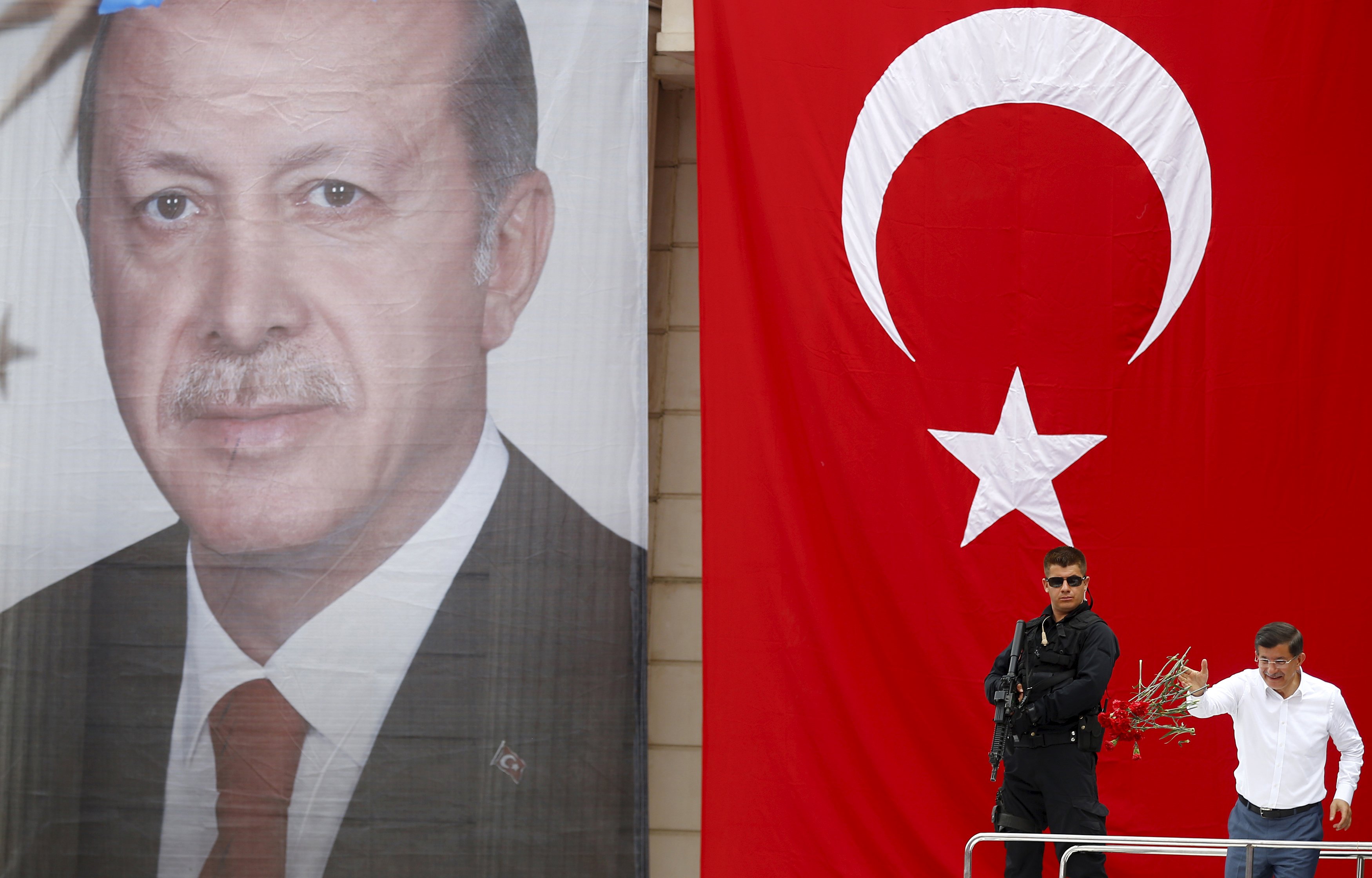 Turkey's Prime Minister Ahmet Davutoglu throws carnations to his supporters as he stands in front of a portrait of President Tayyip Erdogan and a national flag during an election rally for Turkey's June 7 parliamentary election in Istanbul, Turkey, June 3, 2015. Turkey holds a parliamentary election on June 7 that could reshape its political landscape. Erdogan hopes the result will help move Turkey towards a presidential system, while the pro-Kurdish opposition is aiming to enter parliament as a party for the first time. REUTERS/Murad Sezer