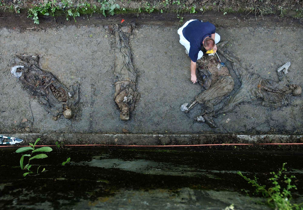 ZUM 20. JAHRESTAG DES MASSAKERS IN SREBRENICA AM SAMSTAG, 11. JULI 2015, STELLEN WIR IHNEN FOLGENDES BILDMATERIAL ZUR VERFUEGUNG - Bosnian Forensic expert Murat Hurtic members of Bosnian Commission for Missing Persons, inspect body remains found at mass-grave site in the village of Sandici near Eastern-Bosnian town of Bratunac, 50 kms north of Sarajevo, Bosnia, on Wednesday, June 16, 2004. Forensic experts exhumed so far 16 bodies buried in a drainage canal near road to Srebrenica. Most of the remains are believed to be those of Muslims from Srebrenica killed in July 1995 during fall of Srebrenica. Location of this mass grave was announced by The Srebrenica Commission, made up of Bosnian Serb judges and lawyers, was formed last year to investigate who was involved in the 1995 slaughter. Its report was approved on Friday, June 11 by the Bosnian Serb government. (KEYSTONE/AP/Amel Emric)