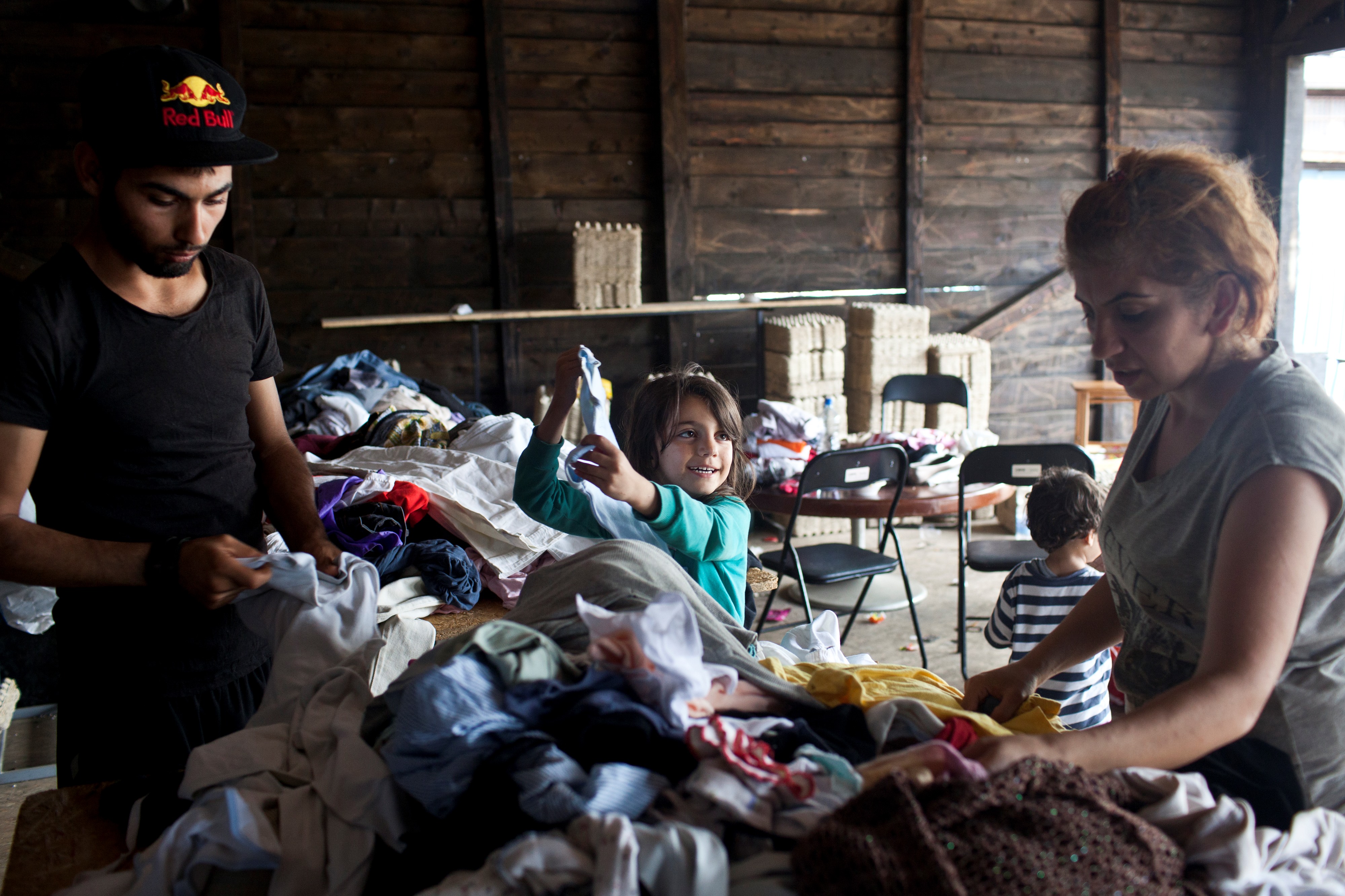 Eine Familie aus Syrien sucht in einem Kleiderdepot, das Einwohner zur Verf�gung stellen // Fl�chtlinge in Belgrad in Serbien auf der Durchreise in die EU. Sie machen Zwischenstopp in der N�he des Bahnhofes in Belgrad befor sie sich auf die Weiterreise in die EU �ber Ungarn machen. // Belgrade, Serbia, 18.08.2015. Asylum seekers are seen in great numbers in the area of Belgrade near the bus and train station. They are taking short rest before continuing their trip towards Hungarian border and further towards western Europe. A family from Syria is seen taking some of the necessities in the nearby depot, where the humanitarian help is gathered for them by local citizens. Photo: Marko Risovic/Kamerades for N-ost