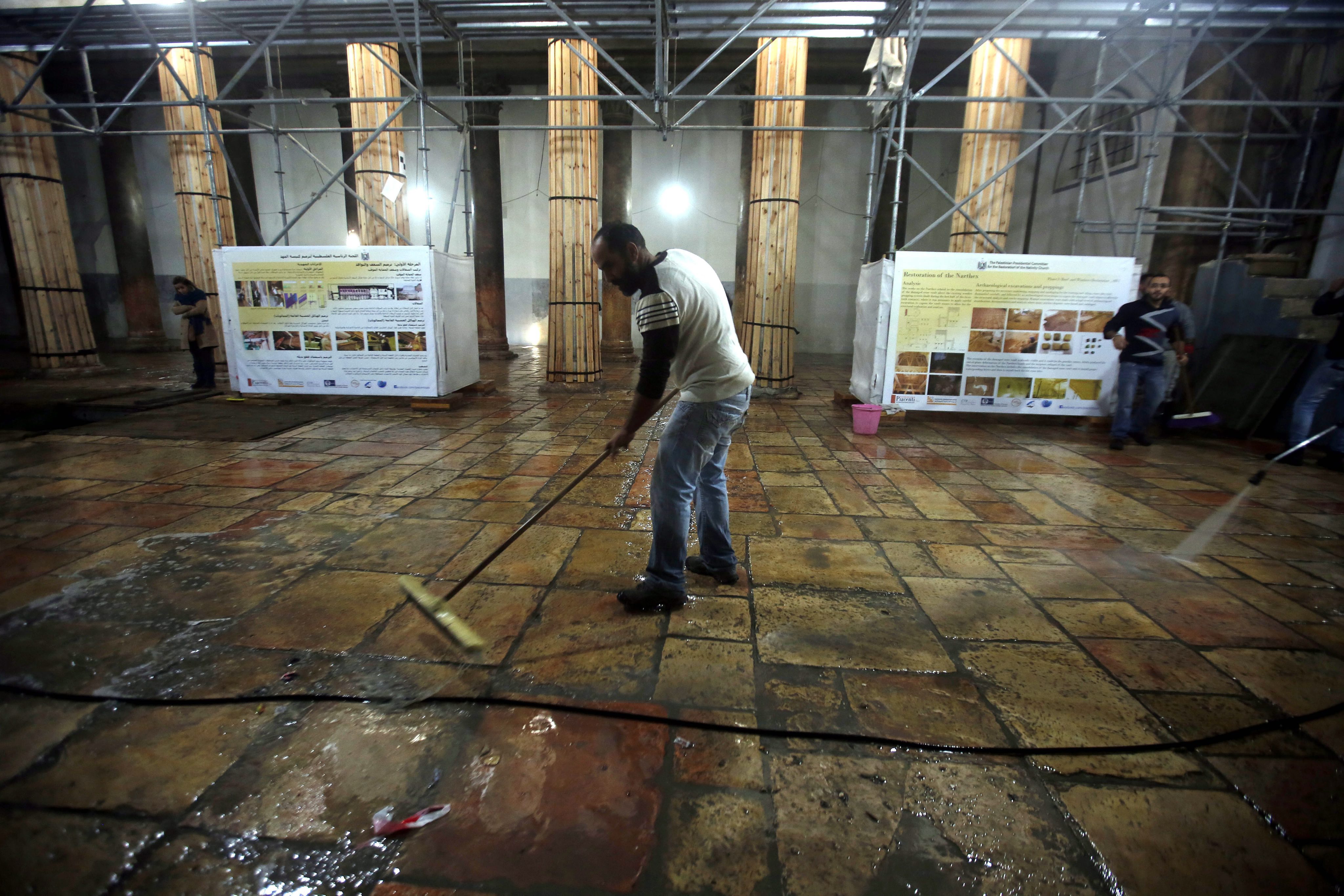 epa05078887 Workers clean the ground at the Church of the Nativity where Christians believe Jesus was born, in the West Bank town of Bethlehem, 22 December 2015. The church where Jesus was born, one of the world's oldest, is still undergoing massive reconstruction work, and is covered in white plastic sheets and scaffolding. EPA/ABED AL HASHLAMOUN