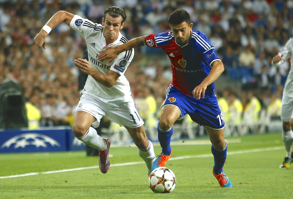 Real's Gareth Bale vies for the ball with Basel's Behrang Safari during the Champions League Group B soccer match between Real Madrid and Basel at the Santiago Bernabeu stadium in Madrid, Spain, Tuesday, Sept. 16, 2014. (AP Photo/Andres Kudacki)