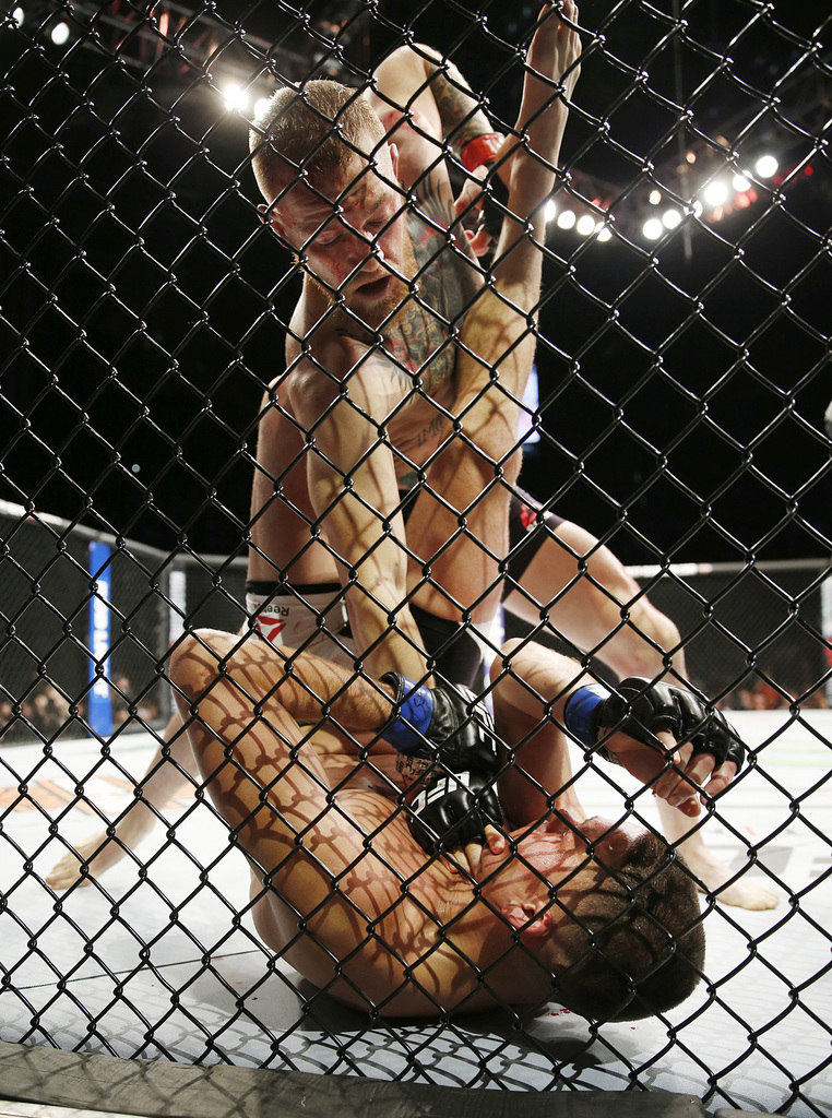 Conor McGregor, top, trades punches with Nate Diaz during their UFC 196 welterweight mixed martial arts match, Saturday, March 5, 2016, in Las Vegas. Diaz won by submission in the second round. (AP Photo/Eric Jamison)