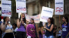 A girl wears a mask as women shout slogans during a demonstration to mark International Women's Day and to demand policies to