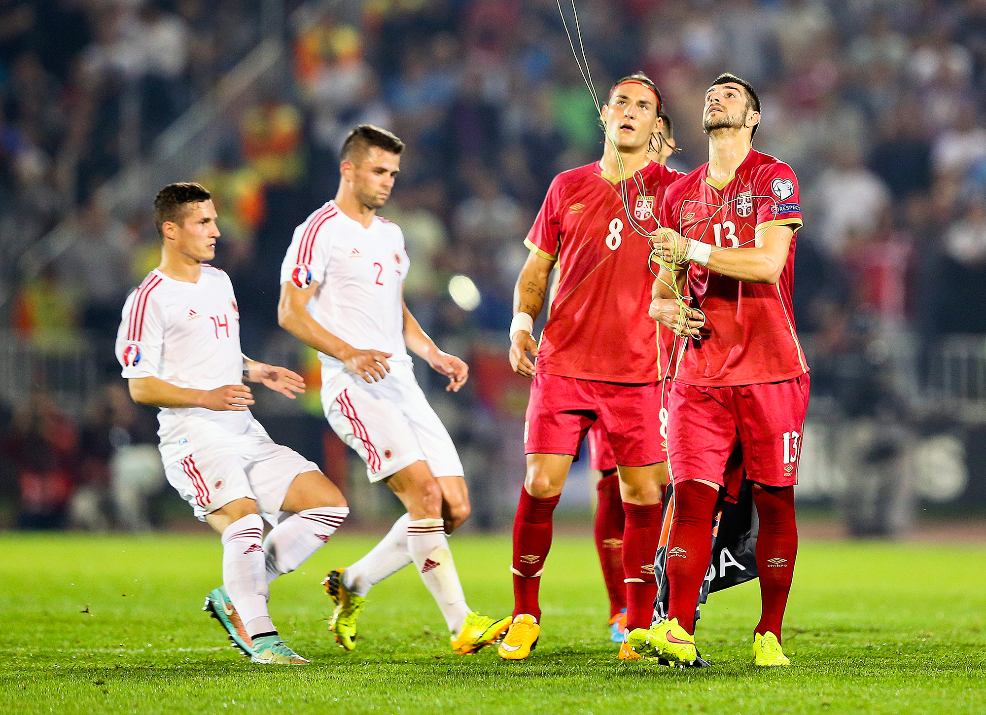 epa04447012 Serbian players try to recover a flag on the pitch before the Euro 2016 Group I qualifying match between Serbia and Albania was suspended, at the Partizan stadium in Belgrade, Serbia, 14 October 2014. The match was suspended after the flag Albanian symbols was flown above the stadium remote controlled by a drone which provoked a fight between players. EPA/SRDJAN SUKI