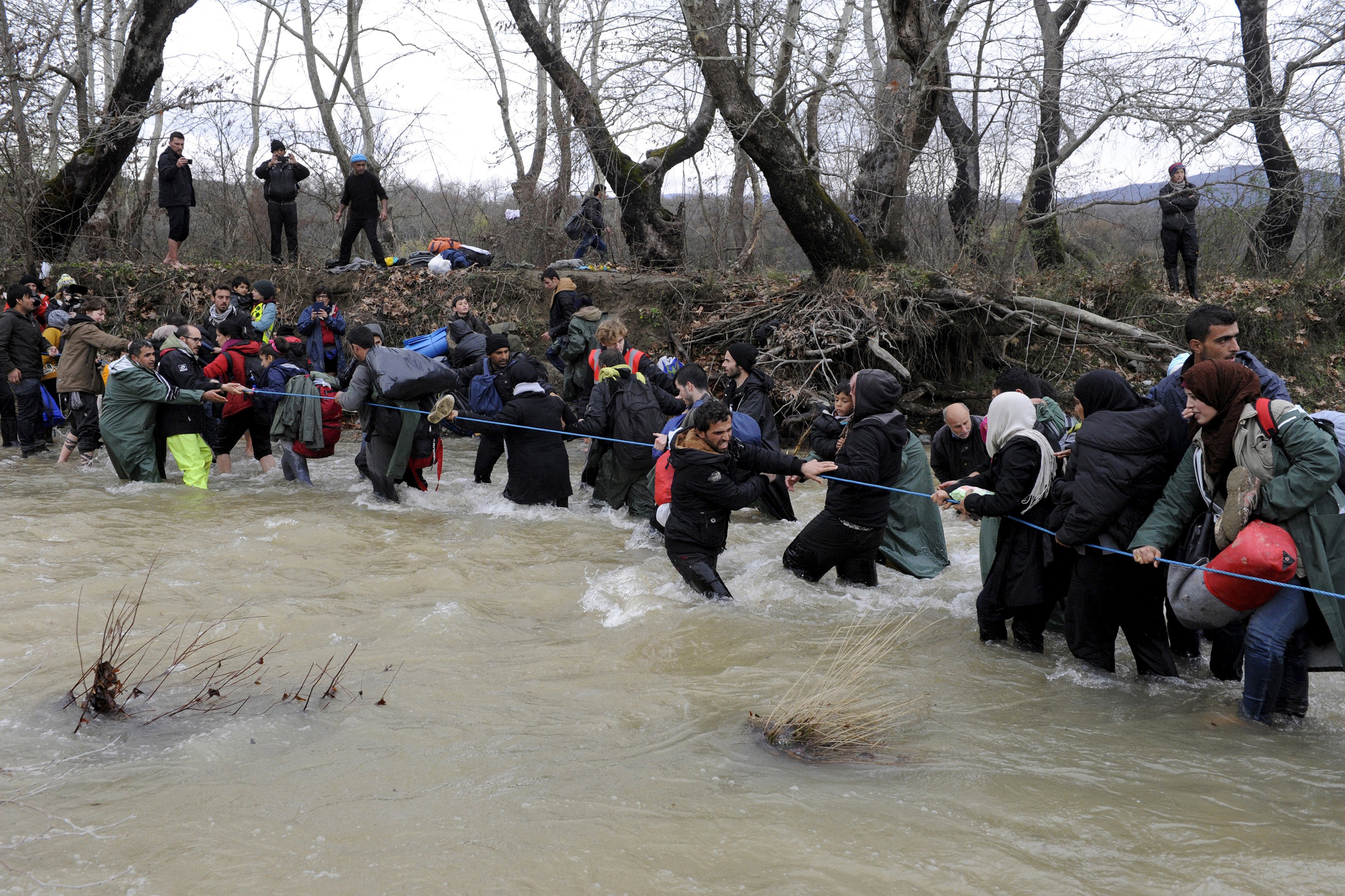 Migrants wade across a river near the Greek-Macedonian border, west of the the village of Idomeni, Greece, March 14, 2016. REUTERS/Alexandros Avramidis