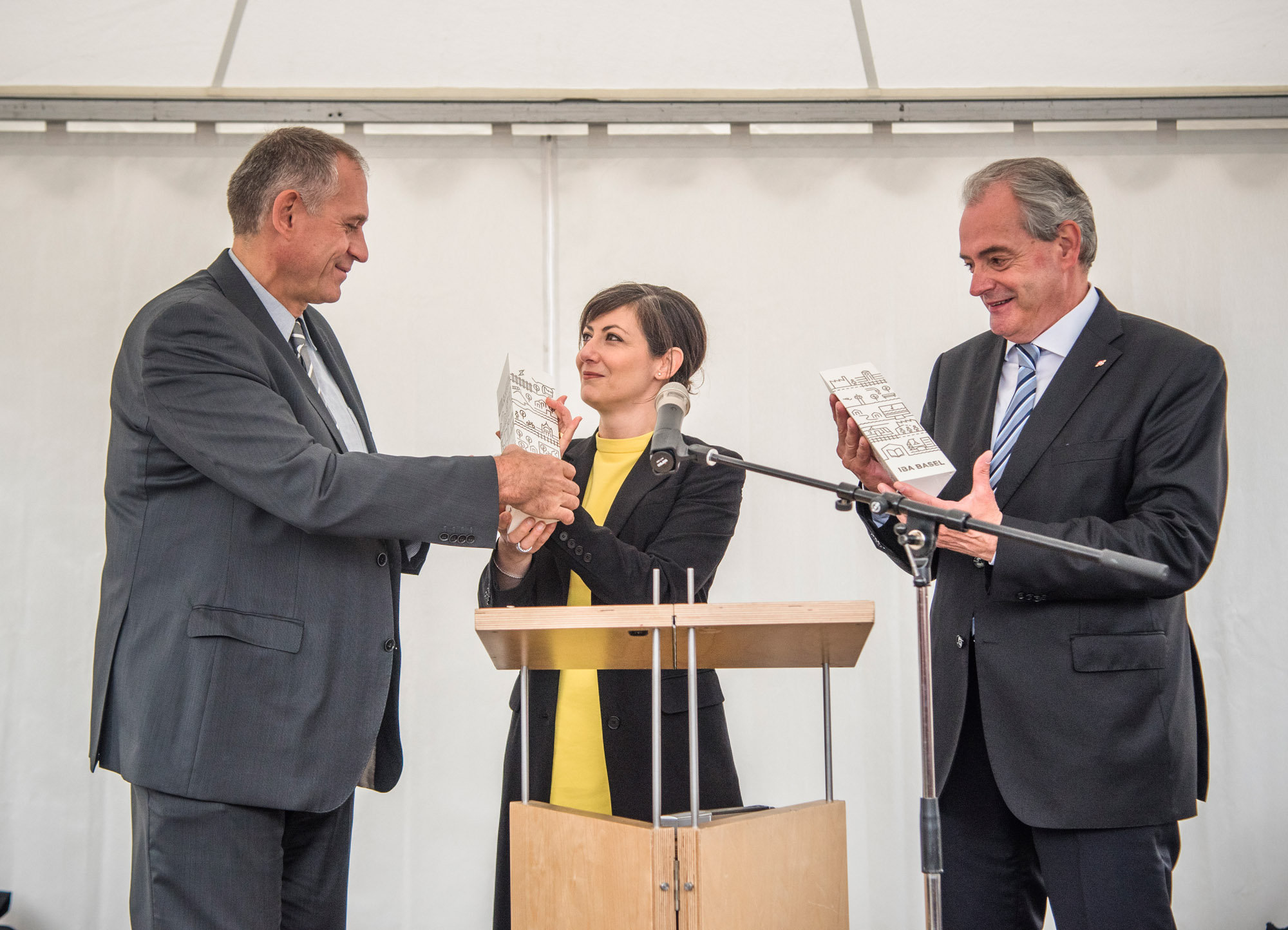 Regierungsrat Hans-Peter Wessels und der Maire von Huningue Jean-Marc Deichtmann erhalten von Monica Linder-Guarnaccia das IBA-Label.