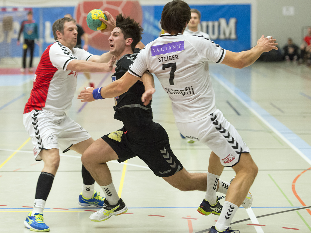 Der Basler Severin Kaiser, Mitte, wird von den Bernern Marco Kurth, links und Benjamin Steiger, rechts, zurueckgehalten im Handball Nationalliga A Meisterschaftsspiel der Swiss Handball League zwischen dem RTV Basel und dem BSV Bern Muri, in der Sporthalle in Birsfelden, am Samstag, 5. Dezember 2015. (KEYSTONE/Georgios Kefalas)