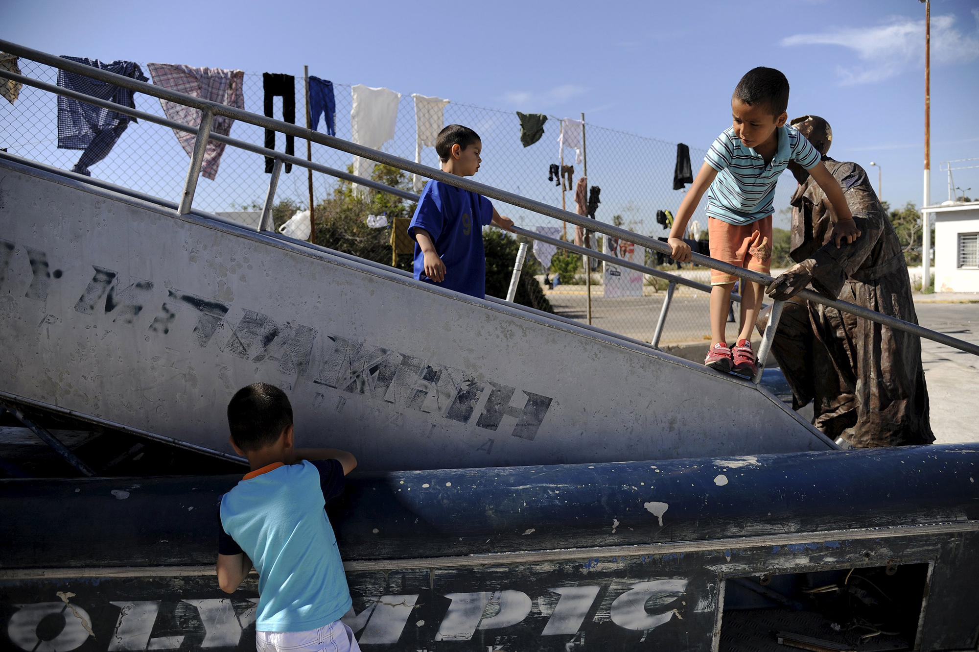 Children play next to an old statue, outside the main building of the disused Hellenikon Airport where stranded refugees and migrants, most of them Afghans, are temporarily accommodated in Athens, Greece, April 17, 2016. REUTERS/Michalis Karagiannis