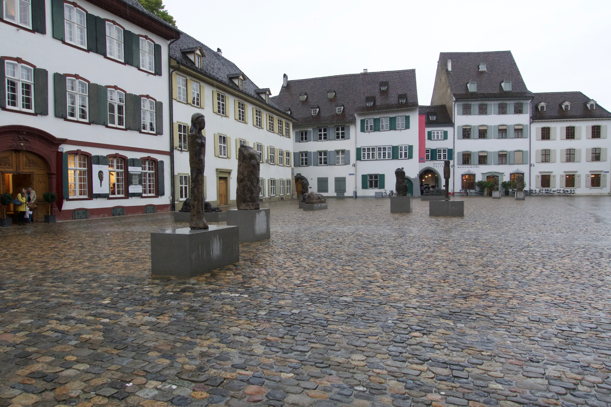 Wartende Menschen zwischen Kathedrale und Absperrgittern: Messingfiguren von Hans Josephsohn.