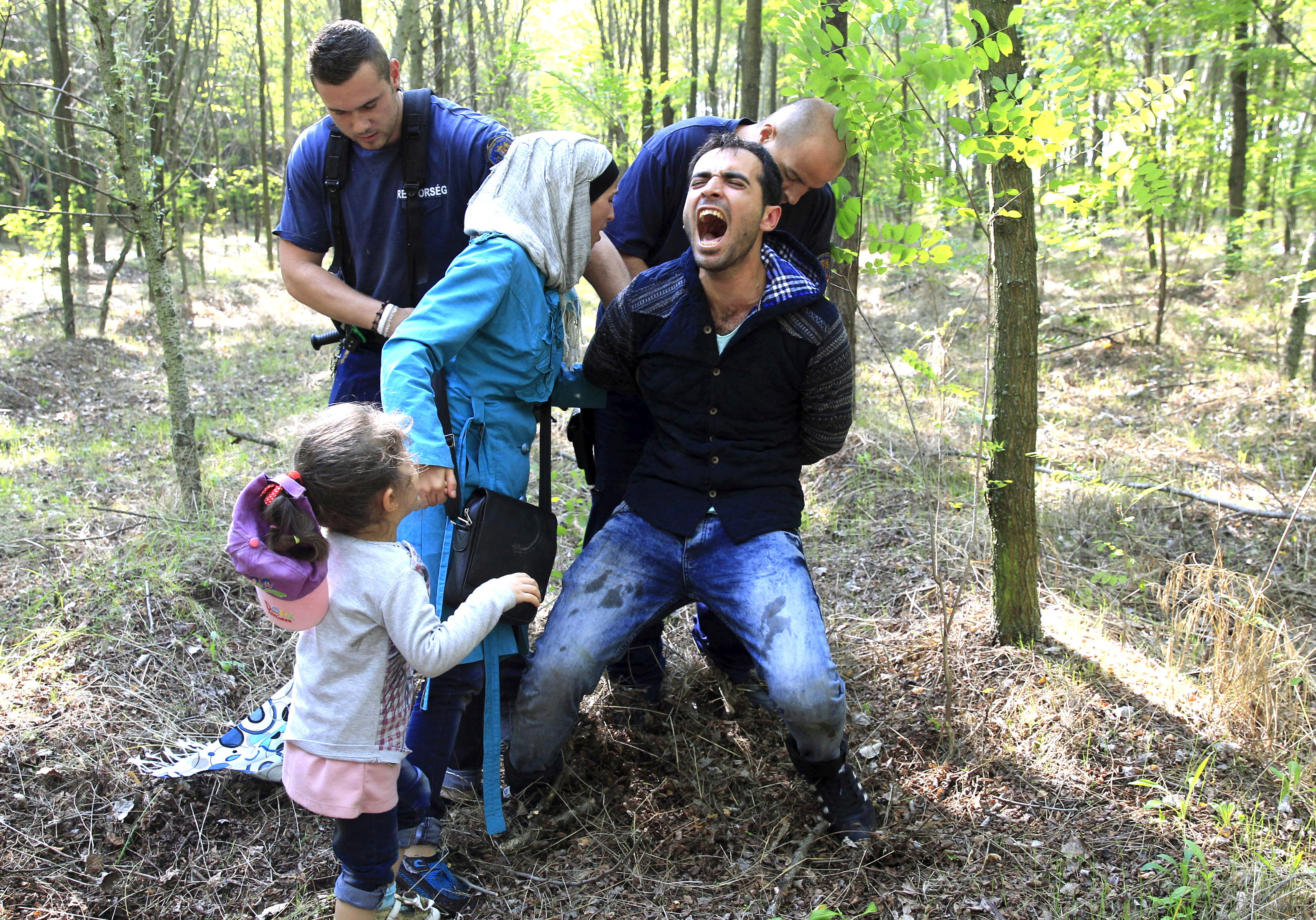 FILE PHOTO: Hungarian policemen detain a Syrian migrant family after they entered Hungary at the border with Serbia, near Roszke, August 28, 2015. REUTERS/Bernadett Szabo/File photo