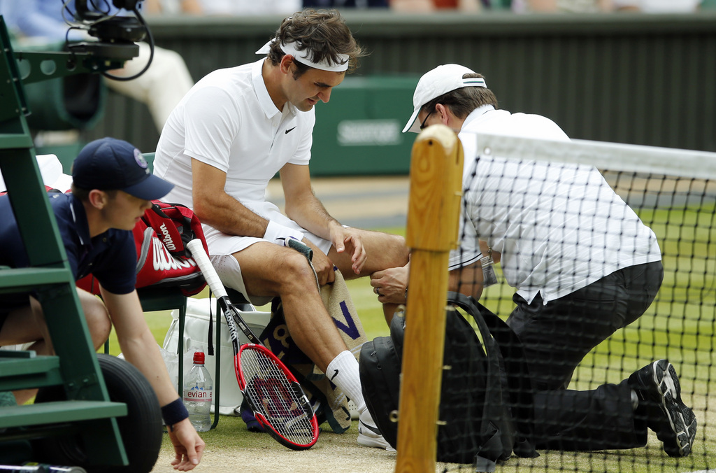 FILE - In this July 8, 2016, file photo, Roger Federer of Switzerland receives medical attention during his men's semifinal singles match against Milos Raonic of Canada at the Wimbledon Tennis Championships in London. Federer says he will miss the Rio Olympics and the rest of the tennis season to protect his surgically repaired left knee. Federer writes Tuesday, July 26, 2016, on his Facebook page that he will skip the Summer Games, where the tennis competition starts next week, and has been advised by doctors to remain sidelined for the remainder of 2016..(AP Photo/Alastair Grant, File)