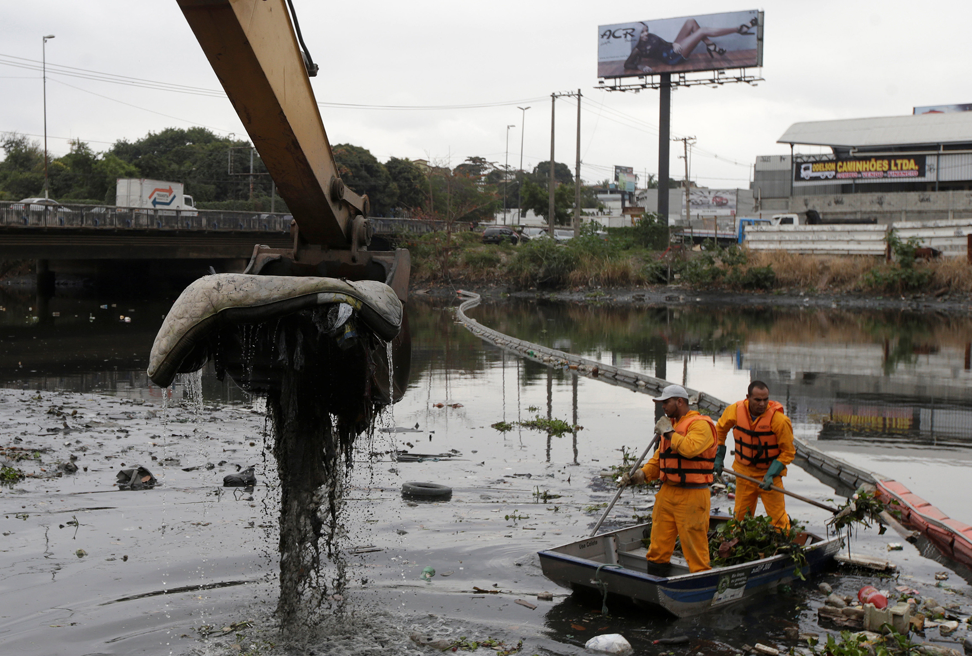 Men work cleaning up the garbage next to an ecobarrier at Meriti River which flows into Guanabara Bay, in Duque de Caxias, near Rio de Janeiro, Brazil, July 20, 2016. REUTERS/Ricardo Moraes