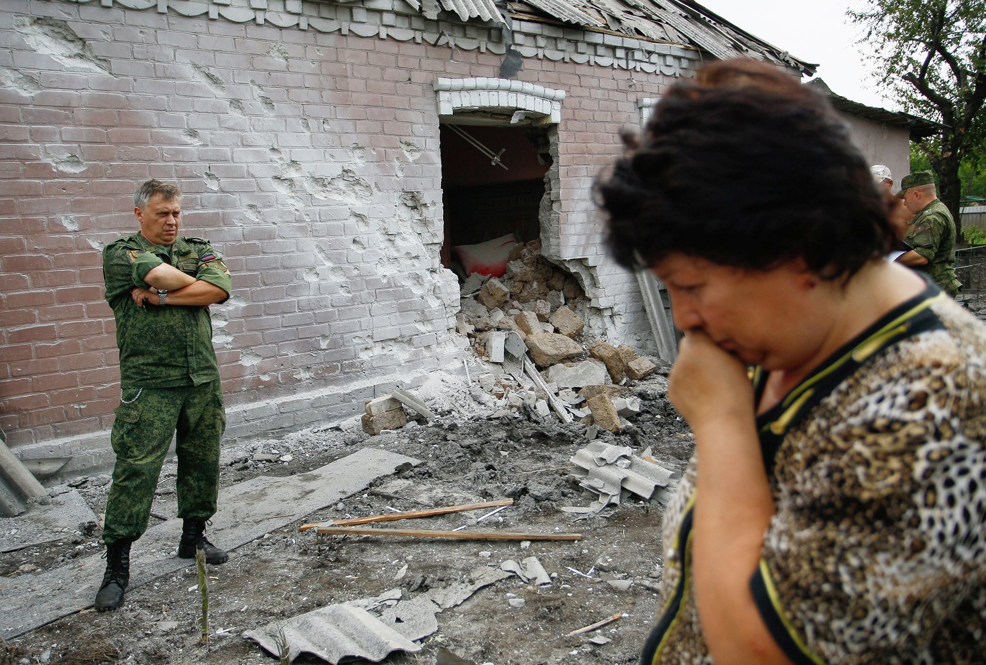 epa05450328 A woman reacts as a pro-Russian rebel stands next to a damaged house after the recent shelling, in Donetsk, Ukraine, 31 July 2016. EPA/ALEXANDER ERMOCHENKO
