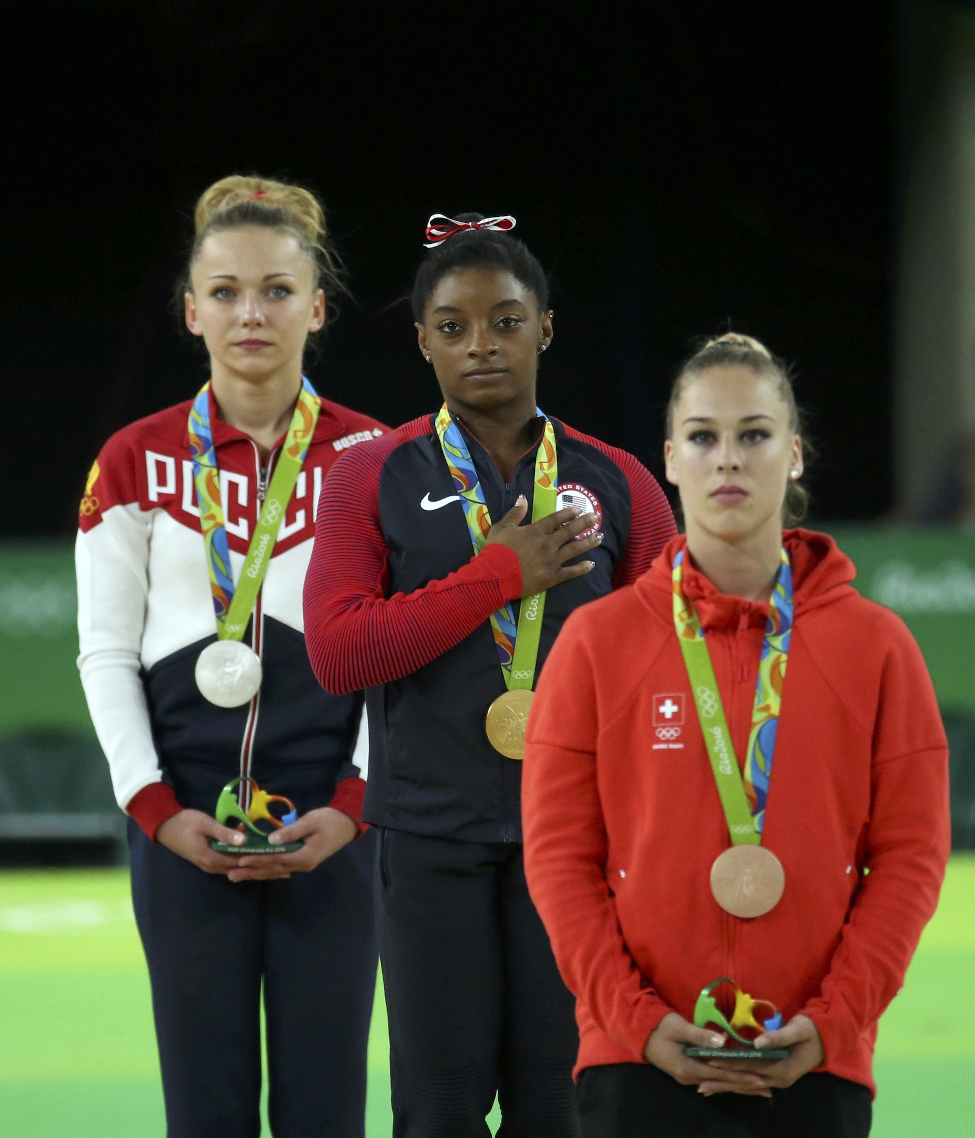 2016 Rio Olympics - Artistic Gymnastics - Victory Ceremony - Women's Vault Victory Ceremony - Rio Olympic Arena - Rio de Janeiro, Brazil - 14/08/2016. Simone Biles (USA) of USA, Giulia Steingruber (SUI) of Switzerland and Maria Paseka (RUS) of Russia listen to the USA anthem. REUTERS/Ruben Sprich FOR EDITORIAL USE ONLY. NOT FOR SALE FOR MARKETING OR ADVERTISING CAMPAIGNS.