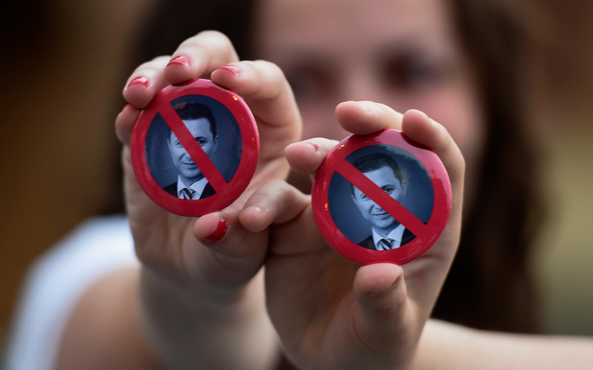 epa04750209 Protestors hold badges with a crossed out portrait of Prime Minister Nikola Gruevski during an anti-government protest in Skopje, the Former Yugoslav Republic of Macedonia (FYROM), 15 May 2015. Macedonian citizens continued their protests after a media conference of the opposition leader Zoran Zaev during which the politician announced a new scandal based on taped conversations of high-ranking officials speaking about alleged irregularities in the government. Under pressure from nationwide protests against his government, Macedonian Prime Minister Nikola Gruevski on 14 May had sacked his interior minister Gordana Jankulovska. The political crisis deepens and the tension is rising ahead of a big anti-government rally set to be held on 17 May in Skopje. EPA/GEORGI LICOVSKI