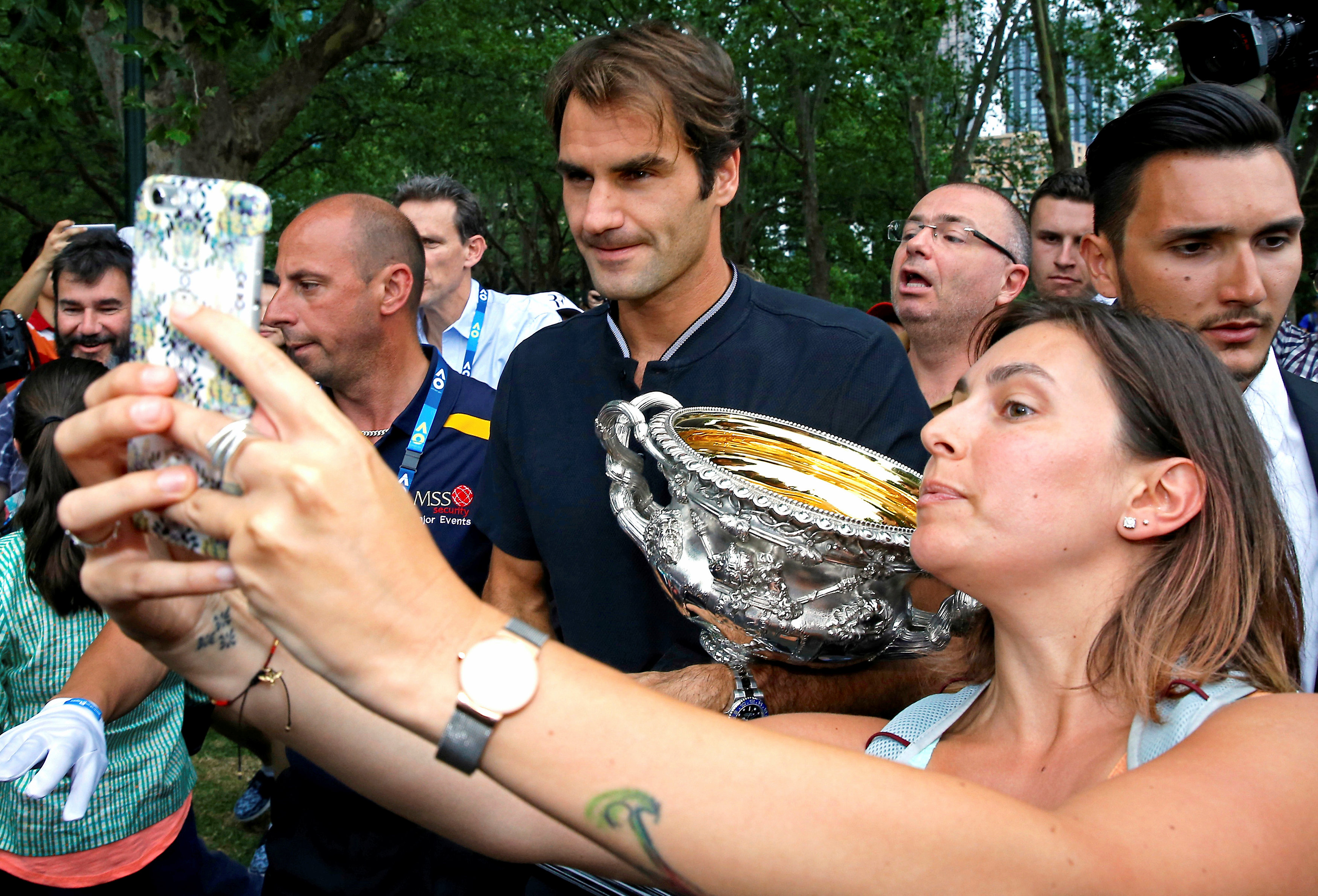 A woman takes a selfie with Switzerland's Roger Federer as he holds the trophy during a photo call the morning after he won the Men's singles final at the Australian Open tennis tournament in Melbourne, Australia, January 30, 2017. REUTERS/Issei Kato