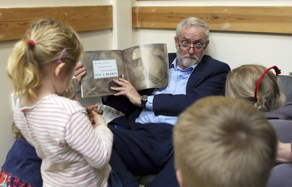 Britain's Labour Party leader Jeremy Corbyn reads with children as he visits Brentry Children Centre in Bristol, western England during Labour's election campaign Friday April 21, 2017. Britain will hold a general election on June 8. (Steve Parsons/PA via AP)