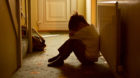 sad child with his head between his legs left alone at home