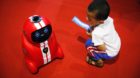 A child holding an entrance ticket watches a smart self-learning robot during the World Robot Conference at the Yichuang Inte