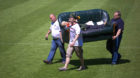 People carry a sofa to set it up on the pitch of the Alte Foersterei stadium for World Cup 2014 public viewing events in Berl