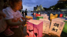 A girl releases paper lanterns on the Motoyasu river facing the gutted Atomic Bomb Dome in remembrance of atomic bomb victims