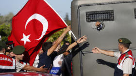 Protesters run after a prison van as an unidentified defendant sticks his fist out as he's driven to a courthouse in Silivri,
