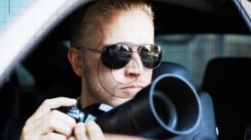 Private Detective Sitting Inside Car Photographing With SLR Camera