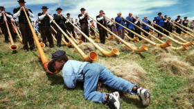 A young lover of the Alphorn kneels down to listen closely to the sound of the Alphorn on the Swiss mountain Maennlichen in t